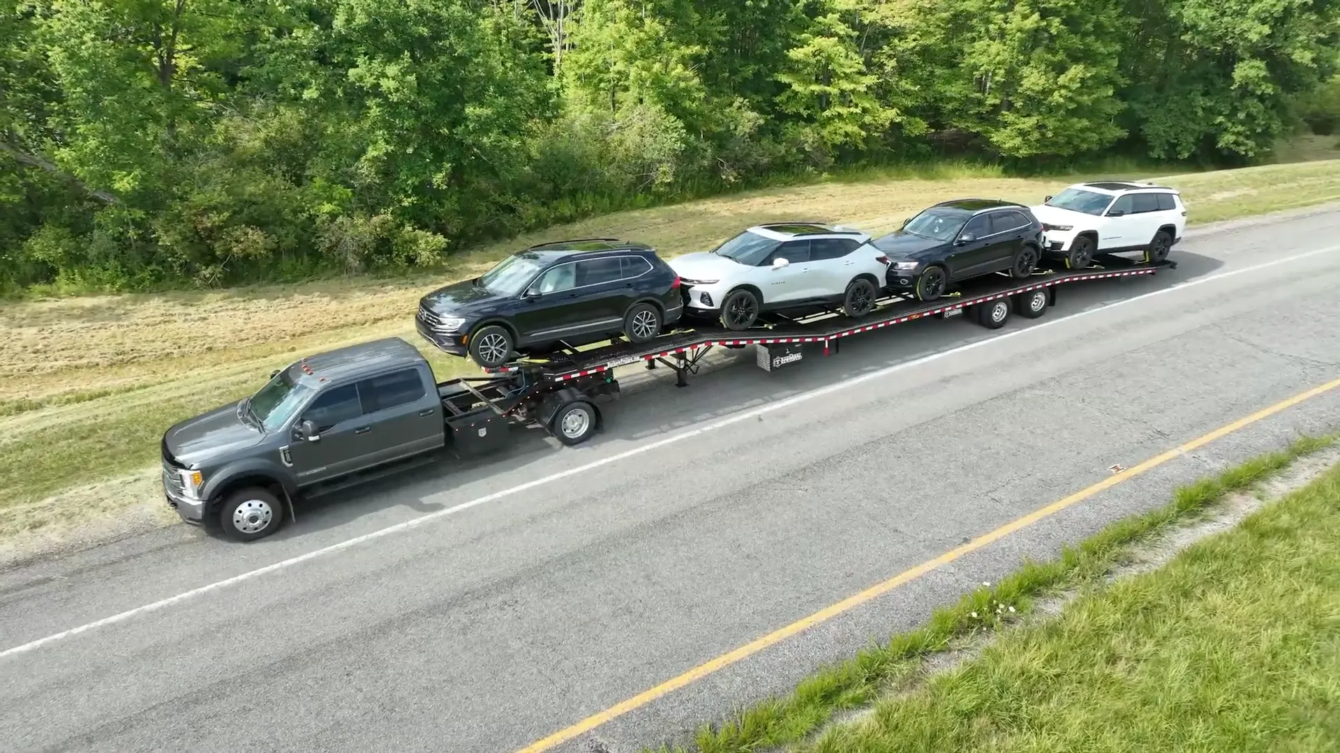Drone shot of a pickup pulling four SUVs on a Buckeye car hauler