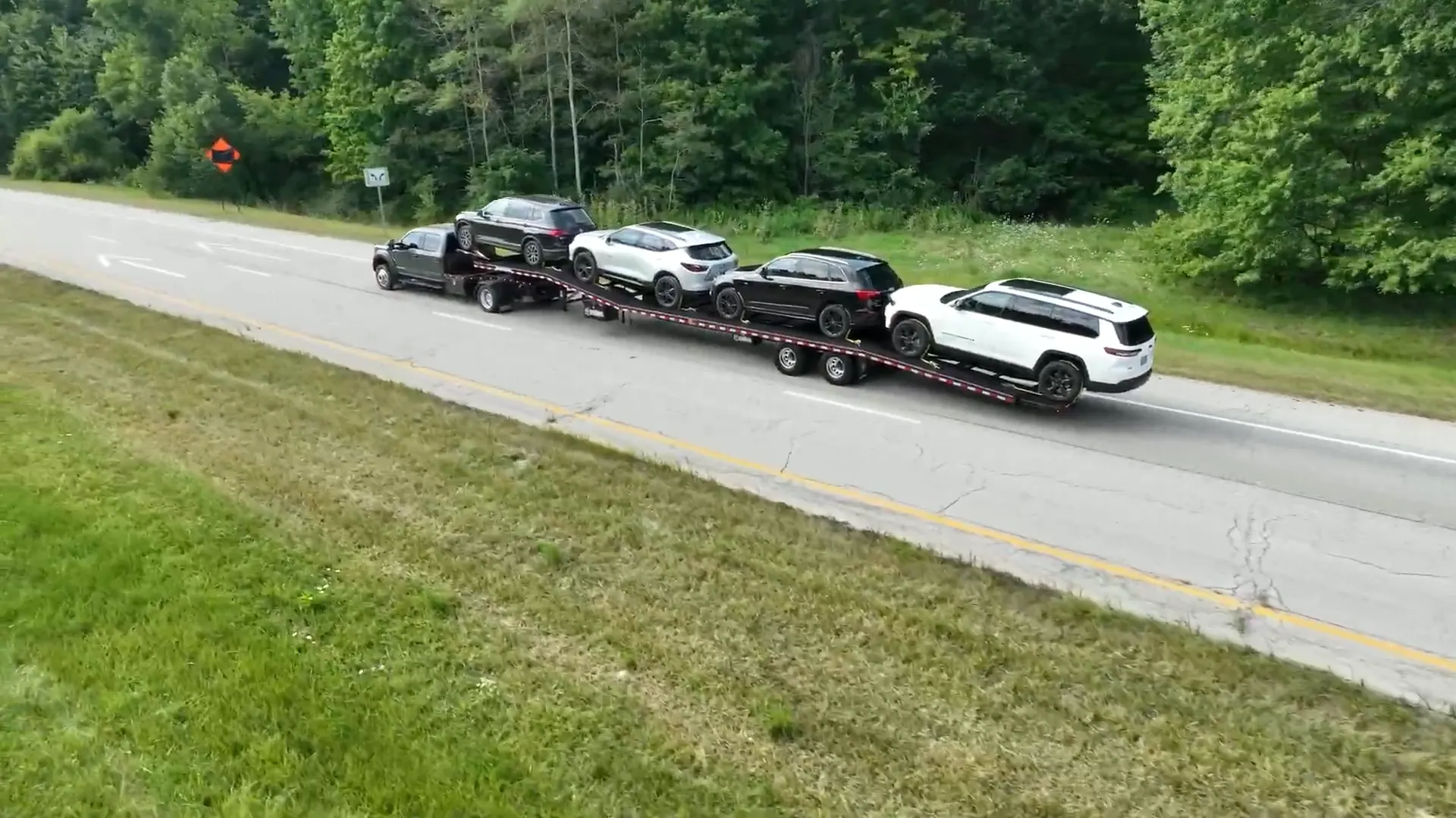 Pickup pulling cars on a Buckeye car hauler around a highway curve