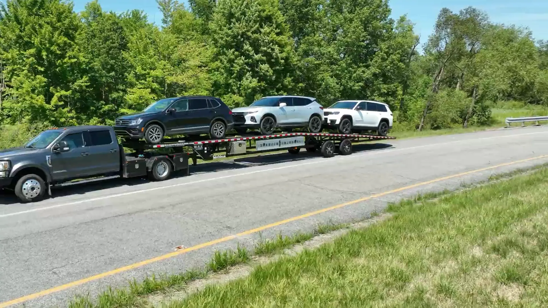 Pickup truck pulling three SUVs on a Buckeye car hauler